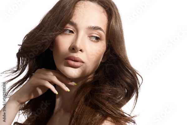 Fototapeta Beautiful young brunette with natural make-up and silk long hair on a white background. Shadow on the face. Woman looking at camera. Isolated over white background.