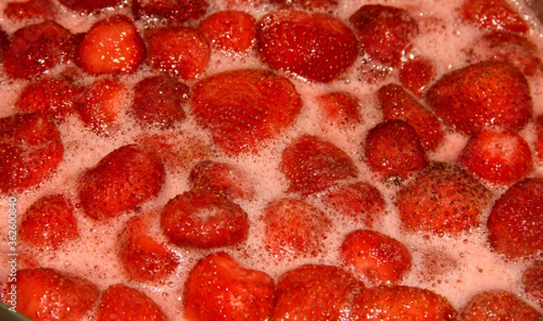 Fototapeta Strawberry jam is being made. A seething mass with berries.