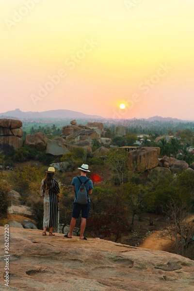Fototapeta Sunset Point at Hampi. The girl and the guy in hats admire the sunset. Golden evening in India.