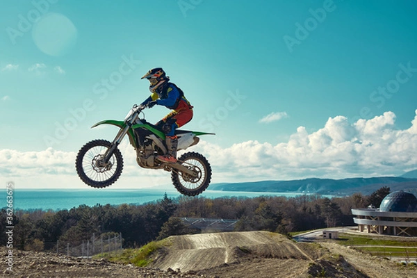 Fototapeta Extreme concept, challenge yourself. Extreme jump on a motorcycle on a background of blue sky with clouds. Copy space, all or nothing.
