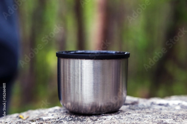 Obraz A mug from a thermos is standing in the woods on a stone.