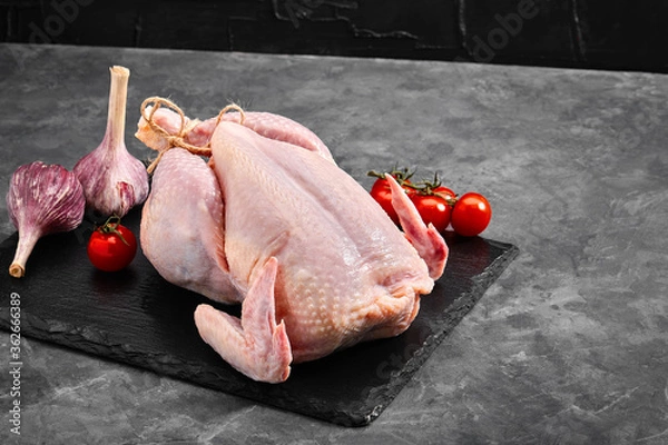 Fototapeta Fresh chicken carcass on a gray background, fresh meat, copy space, photo for grocery stores. dark background