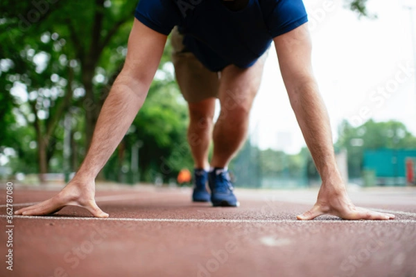 Obraz Athlete man in sportswear in the start position for running. Close up.