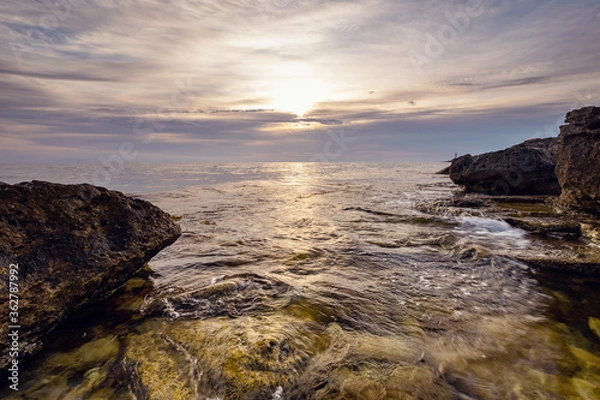 Fototapeta Dramatic sunset over beach with a natural pond in the foreground.