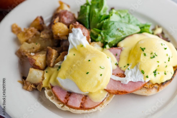 Obraz Eggs Benedict. Traditional classical American diner or French Bistro brunch item. Homemade Hollandaise sauce drizzled over a poached egg, country ham on top of a toasted English muffin with avocado.