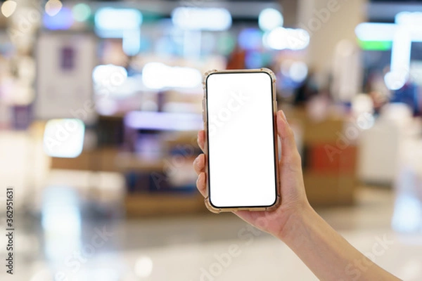 Fototapeta Mockup, hands holding blank white screen mobile phone in blurred department store, digital payment concept