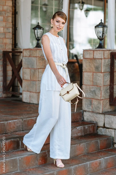 Obraz A girl in a light summer suit with a bag. Demonstration of clothing