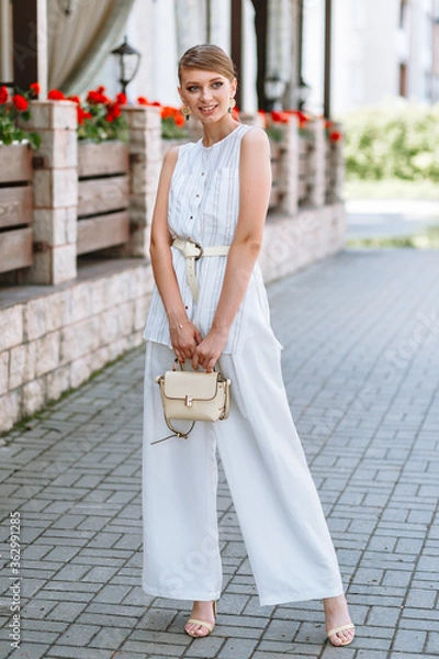 Obraz A girl in a light summer suit with a bag. Demonstration of clothing