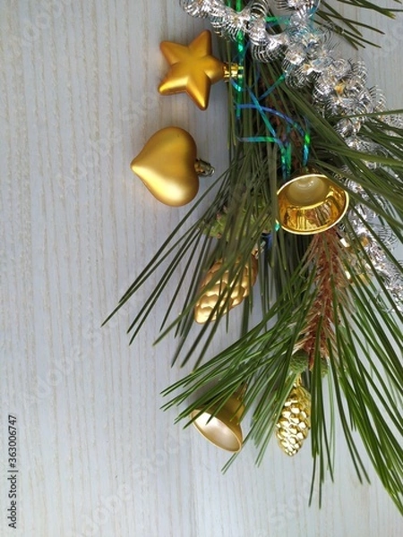 Fototapeta Delicate romantic background for a Christmas card pine branch with gilded christmas toys on the light blue wooden background