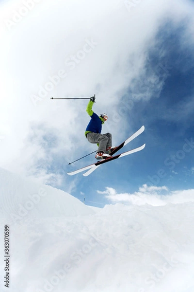 Fototapeta Man doing a mid air ski jump off a mountain