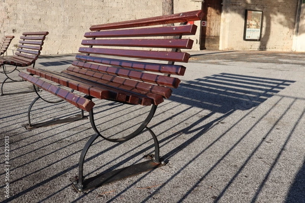 Fototapeta A row of wooden benches with shadows