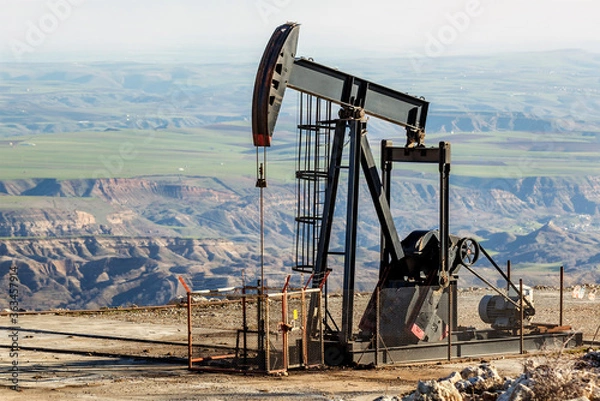 Fototapeta Close up view an oil pumpjack with black color in the mountain of oil rich area. It is used to mechanically lift liquid out of the well if not enough bottom hole pressure exists.