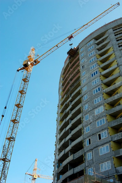 Fototapeta Cranes and building on a background blue sky