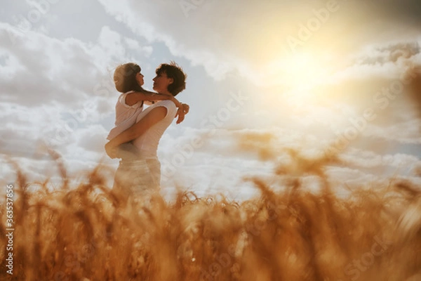 Fototapeta mother and daughter hugging in a wheat field under a sunset