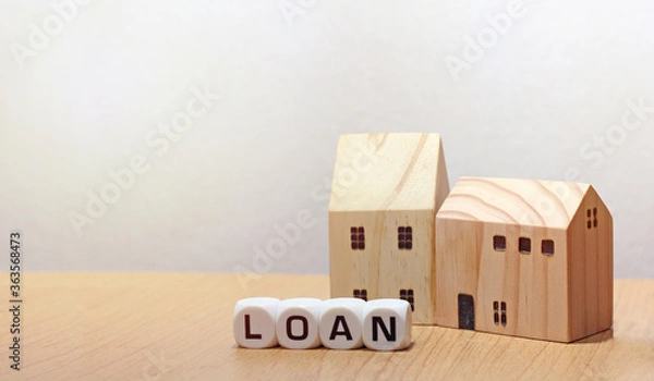 Fototapeta Home loan concept with wood house model on table background. Property investment. Business concept. Dice from the word “LOAN” in front of wood house model. Lone repayment.