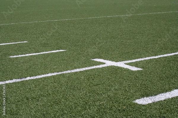 Fototapeta White line markers on a green American football field.