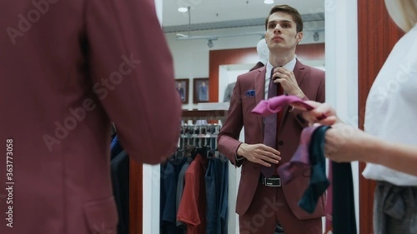 Fototapeta Young businessman looks at the mirror and trys on different ties