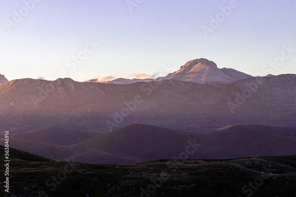 Fototapeta Mountain landscape at sunset with foggy clouds and golden light. Peaceful background and relax landscape. Banner and wallpaper images, backdrop and background with mountain peaceful light