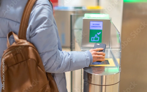 Obraz Electronic Boarding pass and passport control in the airport - hand with boarding pass on smartphone at the turnstile.