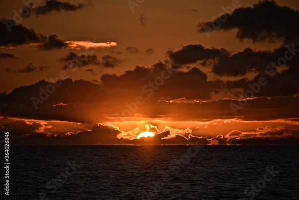 Fototapeta Autumn red sunset over the cold polar sea. Red clouds, illuminated by the cold sun, over the horizon. Photo from the side of the ship.