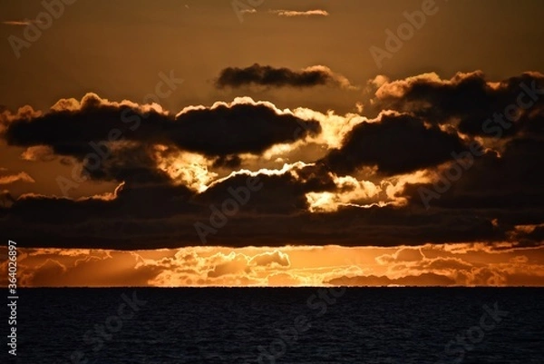 Fototapeta Autumn red sunset over the cold polar sea. Red clouds, illuminated by the cold sun, over the horizon. Photo from the side of the ship.