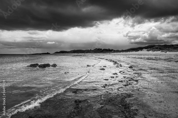 Fototapeta The tide has turned at Low Newton-by-the-Sea but clouds are heavy before the rain on a warm summers day.