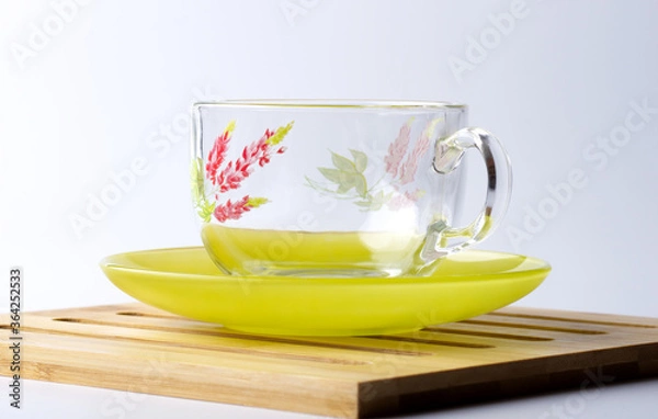 Obraz Glass cup with a floral pattern on a green saucer.