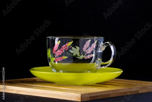 Obraz Glass cup with a floral pattern on a green saucer.