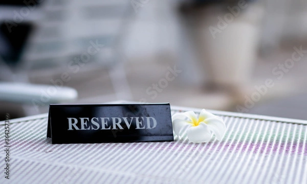 Fototapeta Reserved metal black plate in a restaurant. Reserved metal plate On the white table. vintage photo processing. close up of a setting a reserved sign on the restaurant table.