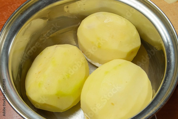 Fototapeta peeled fresh potatoes in a shiny chrome pan