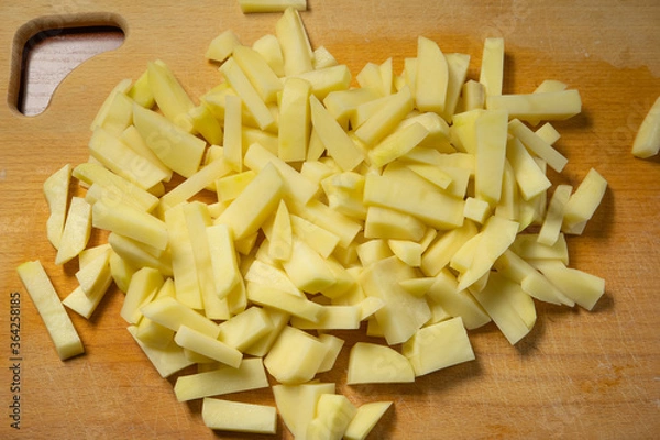 Obraz sliced fresh raw potatoes lying on a kitchen wooden board