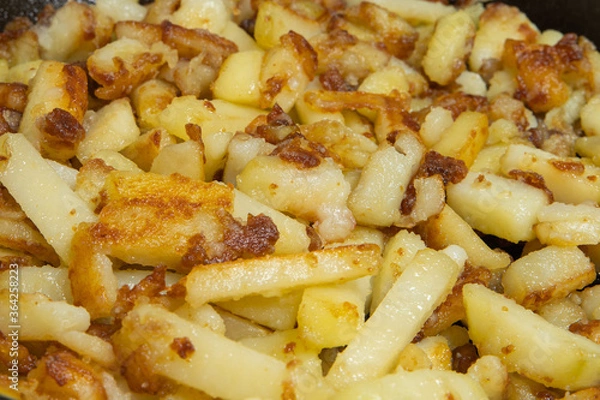 Obraz frying potatoes. chopped potato slices are fried in a pan in oil, close-up. cooking potatoes.