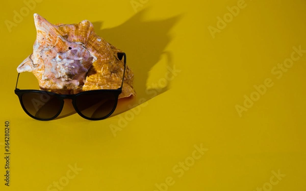 Fototapeta Stylish Sunglasses and Seashell on Bright Yellow Background.