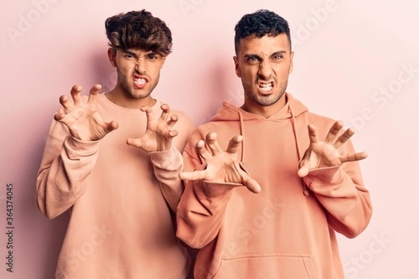 Obraz Young gay couple wearing casual clothes smiling funny doing claw gesture as cat, aggressive and sexy expression