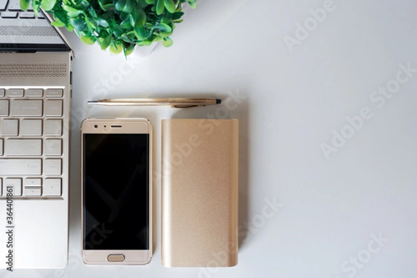 Obraz Neatly arranged gold laptop, smart phone, power bank and pen on white surface. Copy space.