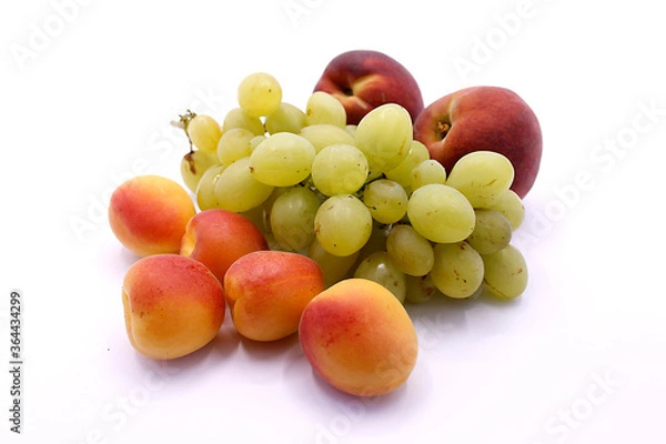 Fototapeta Grape bunch, peaches and ripe apricot close-up on a white background