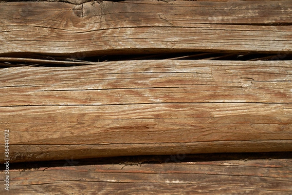 Fototapeta A wall made of natural wood of different sizes and shapes, Log house or barn, textured horizontal walls