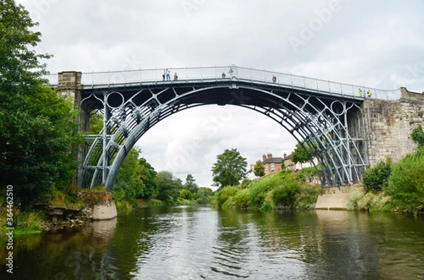 Fototapeta The Iron Bridge at Ironbridge, spanning the River Severn, viewed from low level along the river