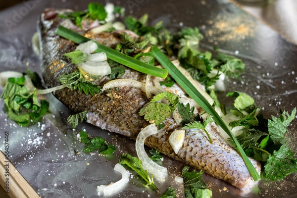 Obraz River fish with onions, herbs, pepper and salt, prepared for baking on barbecue