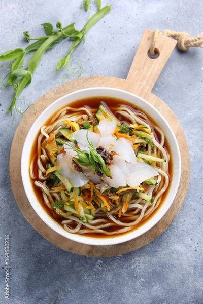 Fototapeta Eastern oriental cuisine, Asian cuisine. Cold soup ashlam fu. Soup with noodles, starch and vegetables. Spicy soup on a light grey background and in a white plate. Background image, copy space