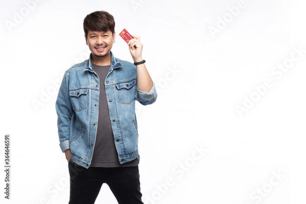 Obraz Asian man in smiley face holding credit card, look at camera, studio light portrait isolated on white background, credit card concept