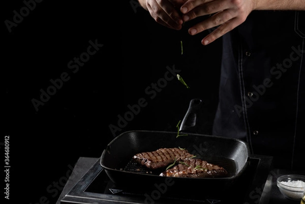 Fototapeta the chef sprinkles beef steak in a frying pan