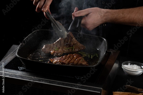 Fototapeta the chef prepares a beef steak in a pan