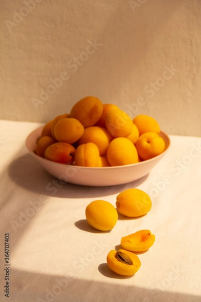 Fototapeta apricots in a plate on a light background in the morning light