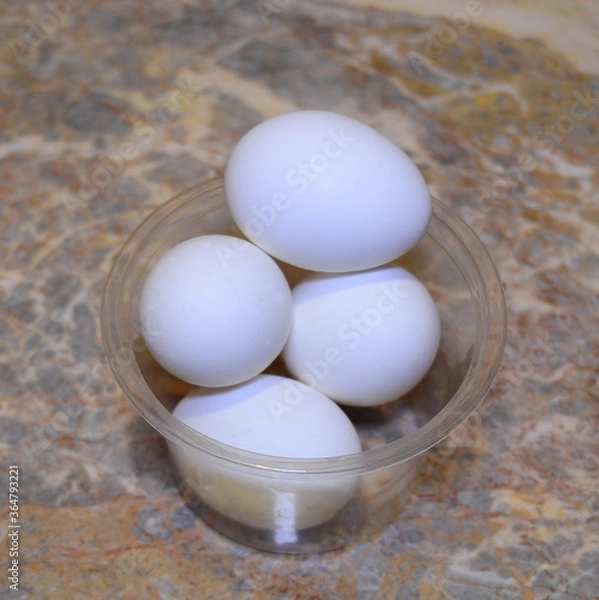 Fototapeta white chicken eggs in a transparent box - delicious and healthy food ingredients, located on a marble surface