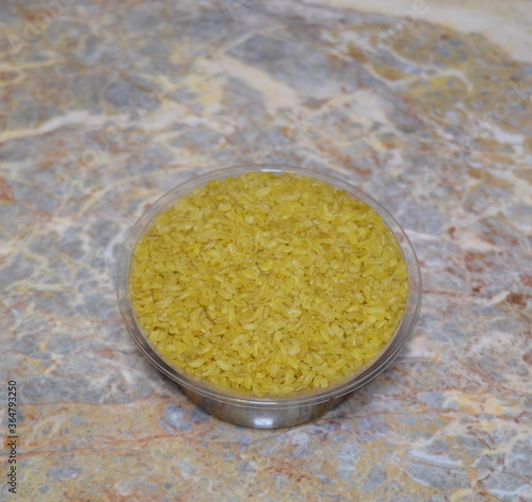 Fototapeta hot yellow bulgur for hot cooking - a useful food ingredient, located on a marble surface