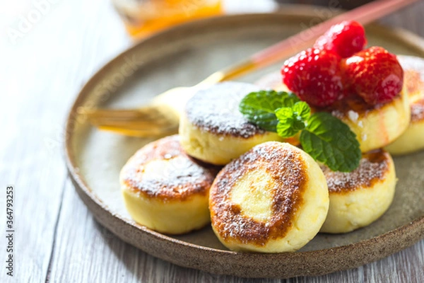 Obraz Cheesecakes with honey and raspberries. Traditional Russian sweet pancakes. Healthy breakfast. Homemade food