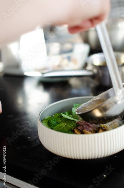 Fototapeta руки повара режут ножом зеленый лук. готовка вьетнамского супа фо бо. вид сверху. свежие натуральные ингридиенты. Национальная еда.