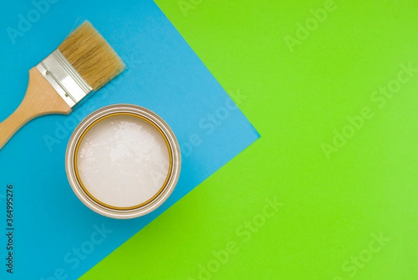 Fototapeta Tools for construction and decoration. A paintbrush and a metal can of paint. Bright background, top view.