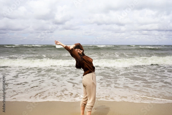 Fototapeta man running on the beach spending leisure time, walking around the beach, watching tide and waves at a Baltic Sea, smiling young woman